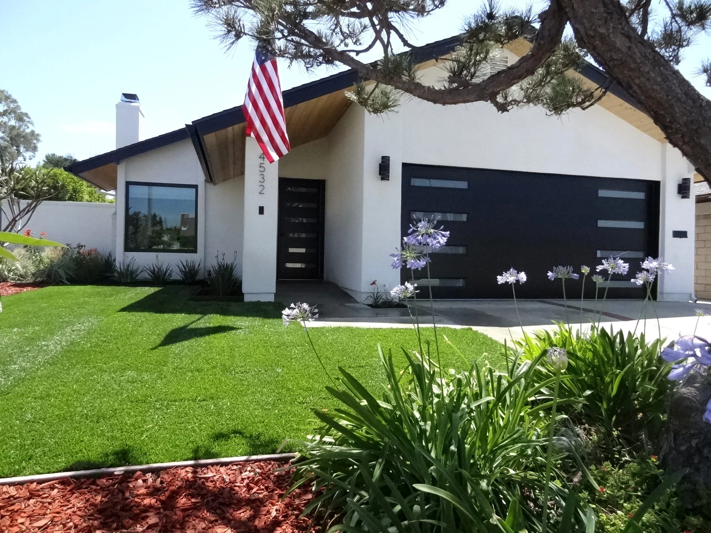 White single-story home with black windows and a modern garage door